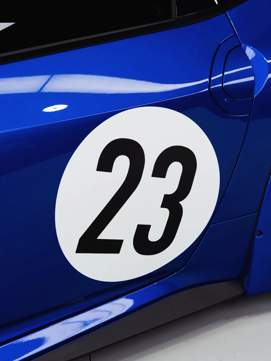 White door circle with race number 23 in black on the blue Nissan Z