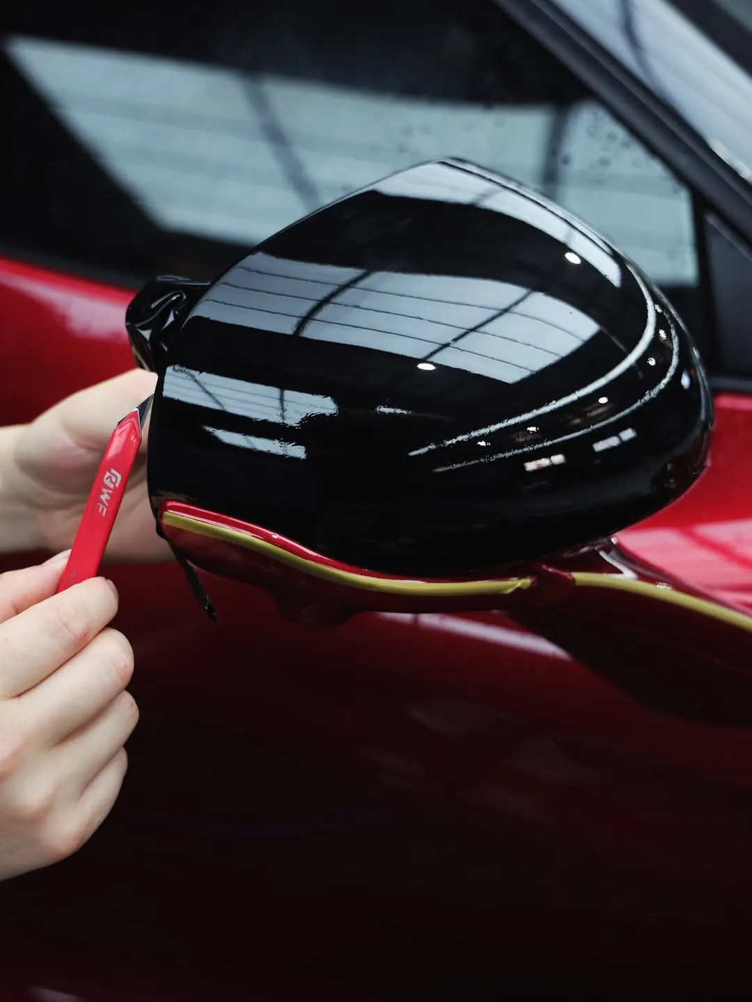 Gloss black film being wrapped onto the mirror of the McLaren 750S
